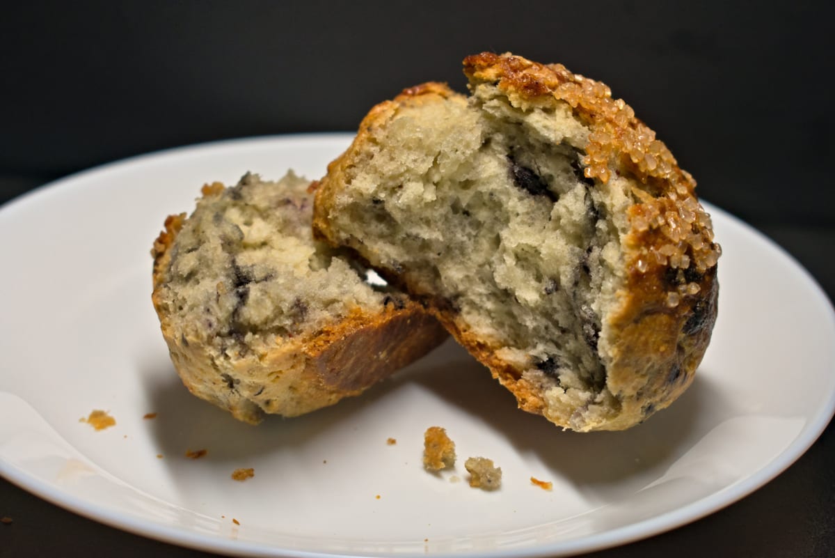 A sugar-topped muffin broken in two on a white plate